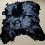Eine ganze schwarze Schaffellmatte. Sofakissen aus Wolle. Eine einteilige Pelzmatte für den Schlafzimmerhocker. Pelzkragen für Lederjacke So ist Leben